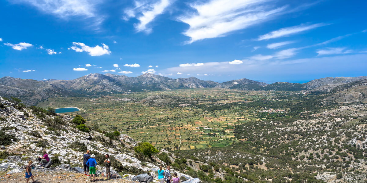 "Panoramic viewpoint over the Lasithi Plateau farmland with the sea visible in the distance"